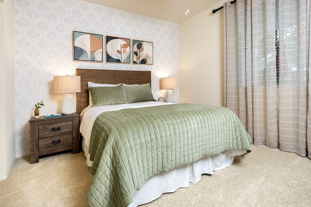 Bedroom with a green quilted bedspread and a cozy nightstand.