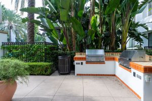 Outdoor grilling station with BBQ grills and tiled counter.