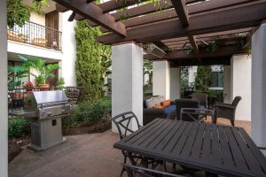 Outdoor grilling station with BBQ grills and tiled counter.