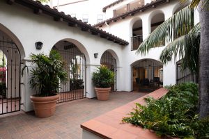 Courtyard of an apartment complex with arches and palm trees at dusk.