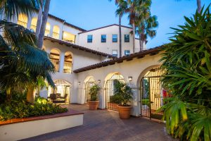 Courtyard of an apartment complex with arches and palm trees at dusk.