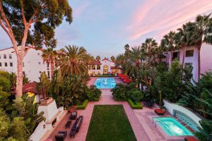 Apartment pool area at sunset with lounge chairs and surrounding buildings.