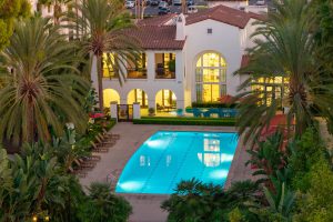 Apartment pool area at sunset with lounge chairs and surrounding buildings.