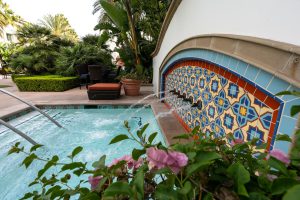 Outdoor spa with a colorful tiled wall and water jets.