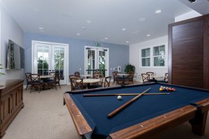 Game room with a pool table and chairs around tables.