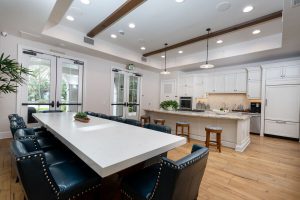 Kitchen with large island, stools, and bright cabinetry.