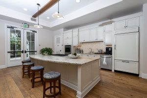 Kitchen with large island, stools, and bright cabinetry.