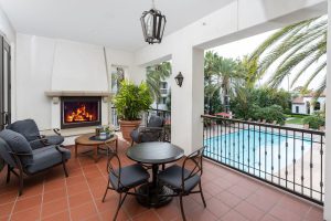 Outdoor lounge area with seating, fireplace, and pool view.