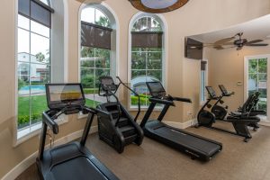 Fitness center with elliptical machines and large windows.
