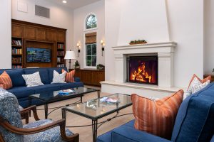 Library room with sofas, a fireplace, and bookshelves.