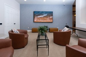 Lounge area with leather chairs and a large TV on the wall.