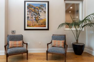 Common area with large windows, comfortable seating, and plants.