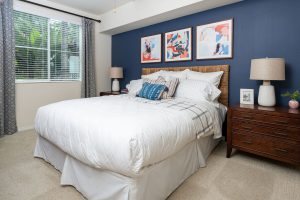 Bedroom with blue accent wall, bed, and desk.