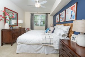 Bedroom with blue accent wall, bed, and desk.
