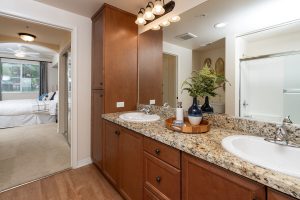 Bathroom with colorful towels, shower, and decorative artwork. Looking into Bedroom with bed.